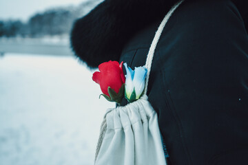 person carrying plastic roses in a white bag