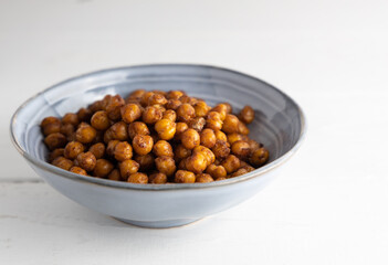 Vegan grilled chickpeas. Homemade vegan chickpeas, Crispy roasted organic chickpeas . Served as a snack in a bowl, on a white background.