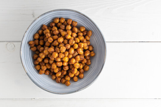 Vegan grilled chickpeas. Homemade vegan chickpeas, Crispy roasted organic chickpeas . Served as a snack in a bowl, on a white background.
