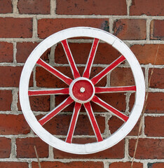 Rot Wei&szlig;es Wagenrad an einer roten Backsteinmauer