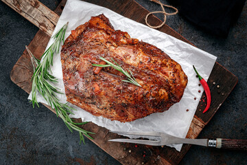 Large piece of baked pork or beef tenderloin with seasonings on a wooden kitchen board