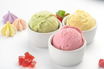 Strawberry, pistachio and lemon ice cream balls in a bowl, isolated on a white background