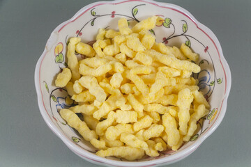 Puffed crackers in a bowl on gray background