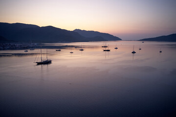 Scenic sunset view with boats on the sea. Mountains and sky in the background. Beautiful marine scene.