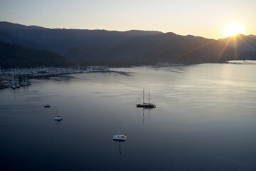 Beautiful view of sea bay during sunset. Landscape panorama with yacht in harbor and mountains in the background.