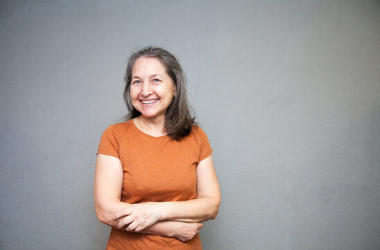 Senior woman in  brown t-shirt studio isolated on grey wall