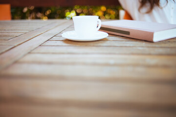 Closeup on cup of coffee and book at table in patio