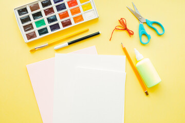 DIY Easter card. Colorful yellow background with paper, stationary. Flat lay top view. Step by step instruction. Create an Easter card with bunny. Children Easter craft. Step 1.