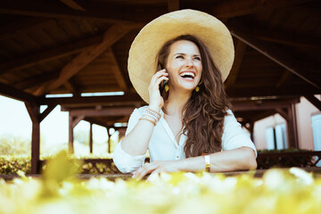 happy stylish woman in white shirt talking on smartphone