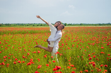 Naklejka na ściany i meble romantic relationship. beautiful couple in love. man and woman in poppy flower field. summer vacation. happy family among red flowers. spring nature beauty. love and romance. We are strong