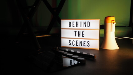 Behind the scenes letterboard text on Lightbox or Cinema Light box. Movie clapperboard megaphone and director chair beside. Background LED color change. static camera in video production studio.
