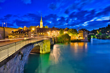 Scenic view of Untertorbrucke bridge in Bern old town with view of Nydeggkirche church. Capital of Switzerland, historic center. Urban cityscape at evening reflecting in the Aare river.