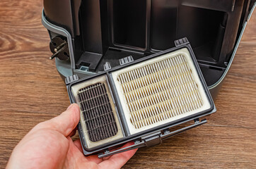 Manual replacement of the air filter in a modern industrial vacuum cleaner. The women removes the...
