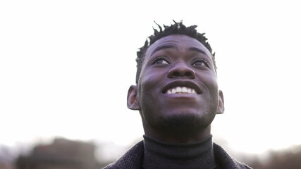 Close-up black man face looking up at sky smiling