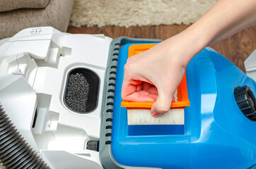Manual replacement of the air filter in a modern industrial vacuum cleaner. The women removes the...