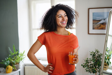 Young woman with healthy drink indoors at home, resting after exercise. Sport concept.