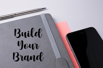 Book, pen and smartphone with build your brand wording.