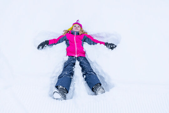 Funny Girl Laying On Snow and Making Snow Angel. High quality photo