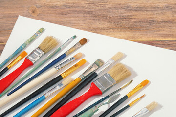 Fototapeta premium Different paintbrushes and white canvas on rustic table. Copy space