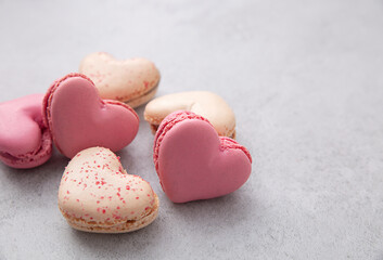 Macarons or French macaroons in heart shapes on gray background with copy space