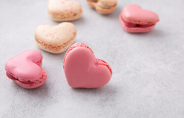 Macarons or French macaroons in heart shapes is a sweet meringue-based confection on gray background with copy space.
