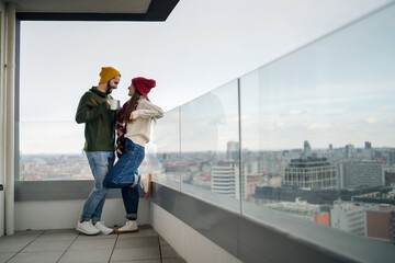 Young couple owners with coffee on balcony in new flat, moving in, new home and relocation concept.