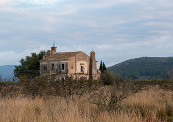 Fototapeta na wymiar Old country house, with mountains in the background and a cloudy sky at dusk