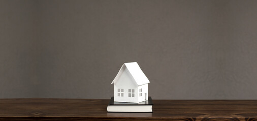 Miniature layout of a white paper house. On the black book