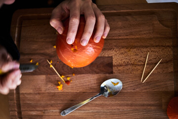 A woman carves a Halloween pumpkin