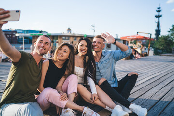 Cheerful friends taking photos on smartphone