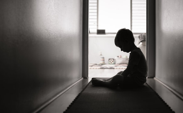 Sad little boy alone in a dark room