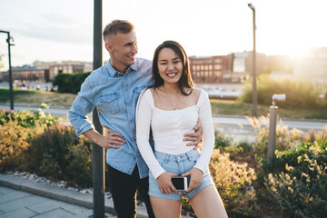 Portrait of cheerful male and female laughing at urban street during date bonding, happy couple in...