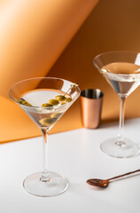 Cocktail vodka martini with green olives on orange background with bright beautiful shadows