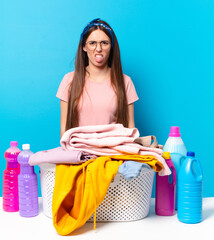 young pretty house keeper feeling disgusted and irritated, sticking tongue out, disliking something...