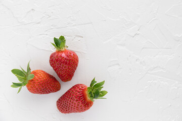 Three Red Strawberries Fresh From the Garden on White Textured Background