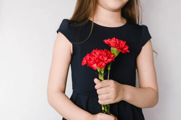 Red carnations in the hands of a child on May 9, Victory Day in Russia.