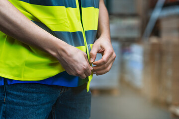Selective focus shot of a male worker buttoning his yellow uniform in a warehouse