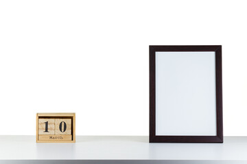 Wooden calendar 10 march with frame for photo on white table and background