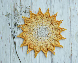 Fototapeta na wymiar Yellow round crocheted napkin, mandala, sun, gradient, symbol on wooden background