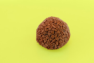 Brigadeiro, handmade chocolate bonbon isolated on yellow background. Brazilian sweet