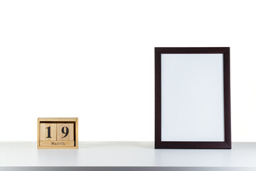Wooden calendar 19 march with frame for photo on white table and background
