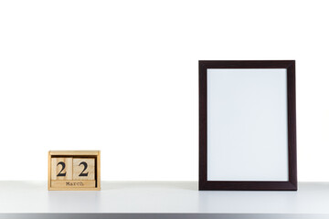 Wooden calendar 22 march with frame for photo on white table and background