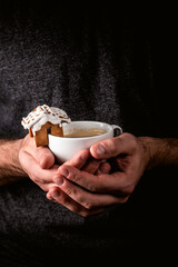 Man holding a white cup of hot coffee with ginger cookie