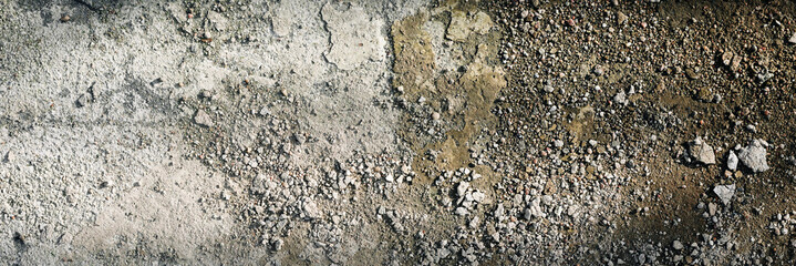 Rough grunge floor surface with small crumbled remains of concrete plaster and small stones. High resolution surface texture illuminated by sunlight. Panoramic banner