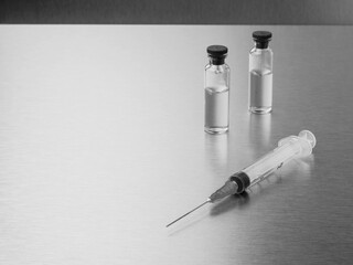 Syringes and ampoules on a polished metal background. Coronavirus vaccination and immunization...