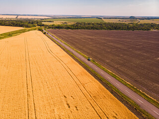 Fototapeta na wymiar Aerial view of a grey asphalted narrow country road.