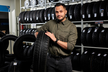 client guy stands with tires by rack of tires, he made choice, buy the best ones in auto service...