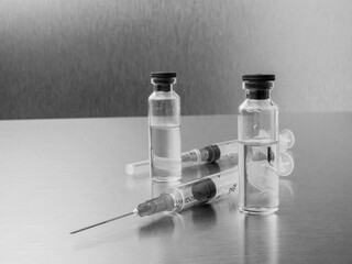 Syringes and ampoules on a polished metal background. Coronavirus vaccination and immunization...