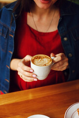 female hands with nails manicure hold a cup of coffee with milk bokeh and blur effect