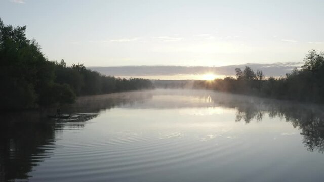 Fisherman in the wood boat at rhe early morning river sunrise